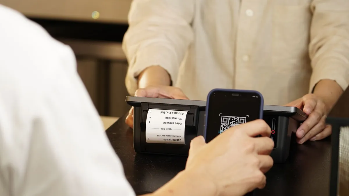 Покупатель оплачивает покупку смартфоном по QR-коду на кассе